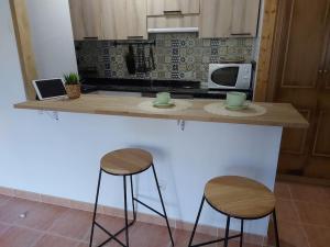 a kitchen counter with two stools and a microwave at APARTAMENTO ESTORDE - COSTA DA MORTE in Cee