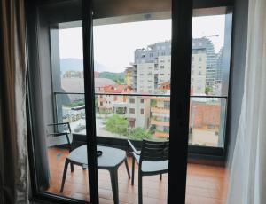 een balkon met 2 stoelen, een tafel en een raam bij Miku Apartment - Unique 3 Bedroom At Olympic Residence in Tirana