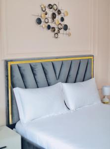 uma cama com cabeceira azul e almofadas brancas em Miku Apartment - Unique 3 Bedroom At Olympic Residence em Tirana
