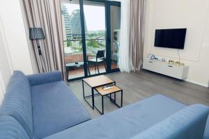 een woonkamer met een blauwe bank en een tv bij Miku Apartment - Unique 3 Bedroom At Olympic Residence in Tirana