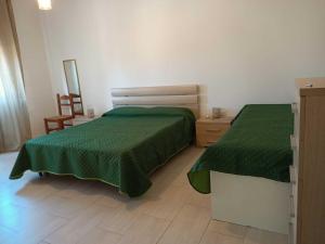um quarto com 2 camas com lençóis verdes e uma cadeira em Casa Antonia em Tempio Pausania