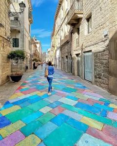 a woman walking down a street with a colorful sidewalk at Casa Antonia in Tempio Pausania