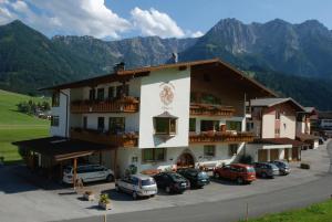a large building with cars parked in a parking lot at Hotel Garni Tirol in Walchsee