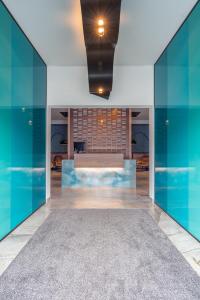 vestíbulo con paredes de cristal azul y sofá en Hotel Traunfall, en Viecht