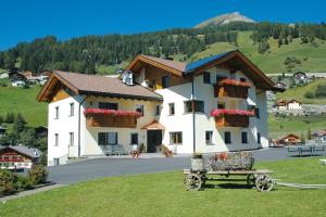 a large white building with flower boxes and a bench at A Sosta in Selva di Val Gardena