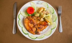 um prato de comida com frango e legumes numa mesa em SKS Inn 