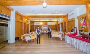 two men standing in a restaurant with tables and chairs at SKS Inn 