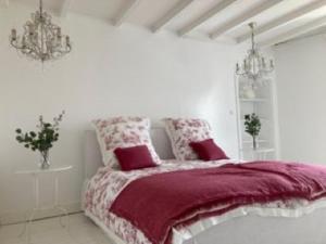 ein weißes Schlafzimmer mit einem Bett mit roten Kissen in der Unterkunft Villa spacieuse très élégante idéale à la détente in Lamargelle