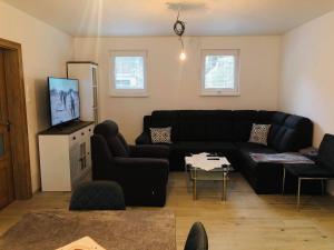 uma sala de estar com um sofá preto e uma televisão em ubytovanie u MITIho em Szalóc