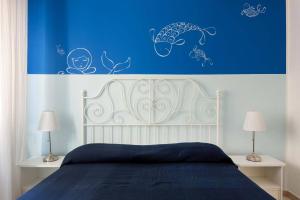 una camera da letto con una parete blu, un letto e 2 lampade di Il Fascino della Sirena - Sea House a Giardini Naxos