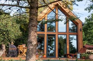 a house with large glass windows and a tree at Zalesie Łany in Zalesie