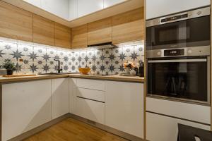 una cocina con armarios blancos y electrodomésticos negros en Porta 25 Guesthouse, en Covilhã