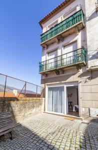 ein Gebäude mit einem Balkon und einer Bank in der Unterkunft Porta 25 Guesthouse in Covilhã