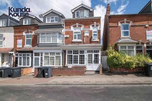 a brick house on a street with trash cans in front of it at Kunda House Dawlish in Birmingham
