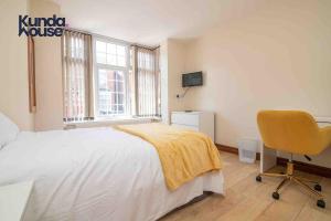 a bedroom with a bed and a chair and a window at Kunda House Dawlish in Birmingham