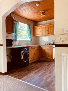 cocina con armarios de madera, lavadora y secadora en 'Melrose' at stayBOOM en Lancaster