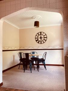 a dining room with a table and chairs and a clock at 'Melrose' at stayBOOM in Lancaster