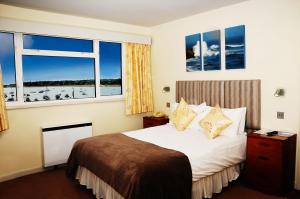 um quarto de hotel com uma cama e duas janelas em Dolphin Hotel em Gorey