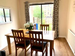 einen Esstisch mit Stühlen und eine Vase aus Blumen in der Unterkunft Dada Apartment in Glasgow