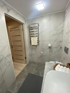 een badkamer met een wastafel, een bad en marmeren muren bij Smerekova Hata in Mizhhirya