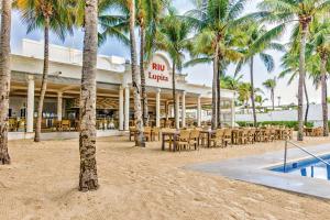 um resort com mesas, cadeiras e palmeiras em Riu Lupita - All Inclusive em Playa del Carmen