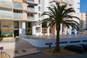 un palmier devant un bâtiment dans l'établissement Bright 1BDR Apartment W/Balcony & Pool by LovelyStay, à Silves