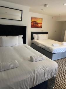 a hotel room with two beds with white sheets at Spacious house with 3 ensuite bedrooms in Leeds in Leeds