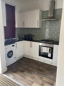 a kitchen with white cabinets and a washing machine at Spacious house with 3 ensuite bedrooms in Leeds in Leeds