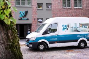 biało-niebieski van zaparkowany przed budynkiem w obiekcie 247 Selfcheckin Pferdemarkt w mieście Leer
