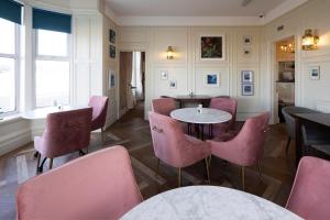 a restaurant with pink chairs and tables in a room at The Beach Club in Penzance