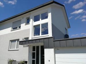 une maison blanche avec une grande fenêtre et un garage dans l'établissement Ferienwohnung Berliner Straße, à Schloß Holte-Stukenbrock