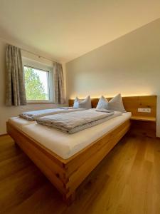 a bedroom with a large wooden bed with a window at Pension & Gasthof zur Taube in Sulzberg