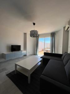Preciosa vivienda con gran terraza muy luminoso في غرناطة: غرفة معيشة مع أريكة وطاولة قهوة