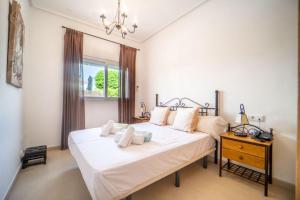 ein Schlafzimmer mit einem großen weißen Bett und einem Nachttisch in der Unterkunft Villa con Piscina Privada de La Torre Golf Resort Murcia - CA13LT in Torre-Pacheco + 38 Fotos