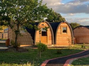 a house with a wooden door and a fence at Squirrel Glamping Pod School House Farm in Leighton