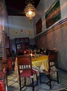 uma sala de jantar com uma mesa e cadeiras e um lustre em Riad Rchacha em Fez