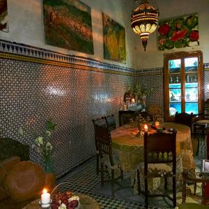 uma sala de jantar com uma mesa e cadeiras e um lustre em Riad Rchacha em Fez