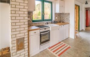 a kitchen with white cabinets and a brick wall at Nice Apartment In Nowe Warpno With Wifi in Nowe Warpno