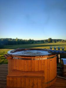 a wooden hot tub on a deck with a table at Unique Countryhouse & Sauna in Gauja Valley - Kaķukalns in Straupe