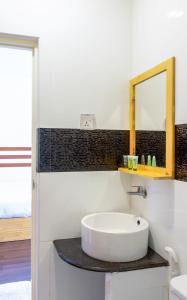 La salle de bains blanche est pourvue d'un lavabo et d'un miroir. dans l'établissement Green Leaf Guest House - Omadhoo, à Omadhoo