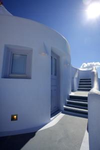 a white hallway with stairs and a door and a stair case at Ikastikies Suites in Firostefani