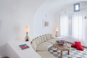 a white living room with a couch and a table at Ikastikies Suites in Firostefani