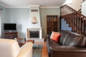 uma sala de estar com um sofá de couro e uma lareira em Ocean Breeze Villa em Atouguia da Baleia