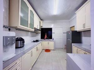 a kitchen with white cabinets and a black refrigerator at Homestay Ampang Farah in Ampang