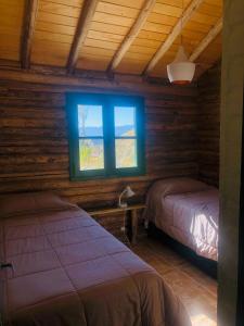 a bedroom with two beds and a window at Cabañas del Mesón in Potrerillos