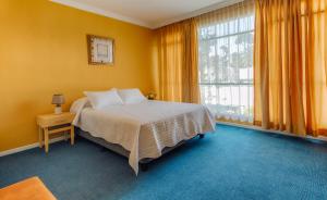Casa Carrión في كيتو: غرفة نوم بسرير وجدران صفراء ونافذة
