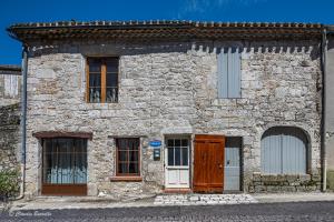 a stone building with two doors and windows at Bastide de Tournon d'Agenais in Tournon-dʼAgenais