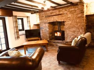 uma sala de estar com mobiliário de couro e uma lareira de pedra em Cobblers Cottage in Brecon Beacons em Brecon