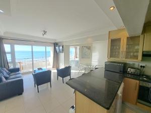 a kitchen and living room with a view of the ocean at 3 Bedroom Sea Facing Family Apartment Cape Town Moullie Point in Cape Town