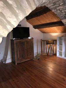 sala de estar con TV y suelo de madera en Maison de village au cœur des remparts en Sainte-Eulalie-du-Cernon